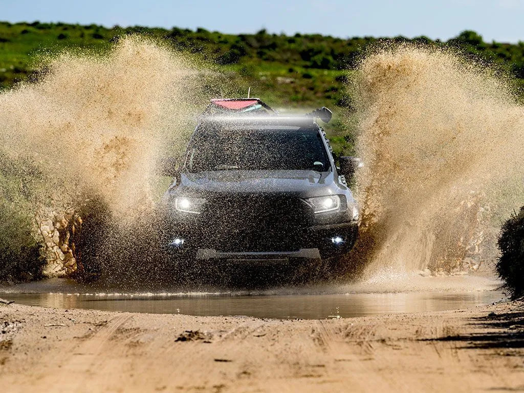 SUV driving through a muddy water puddle on a dirt road