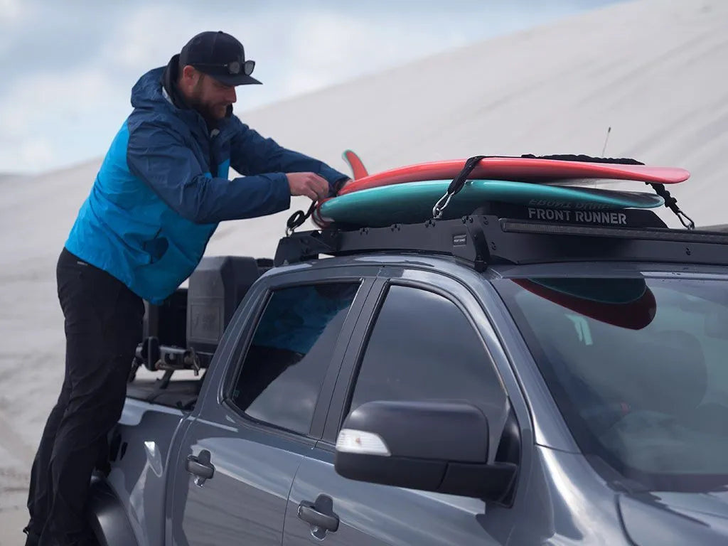 Person loading surfboards onto a car with a desert landscape in the background