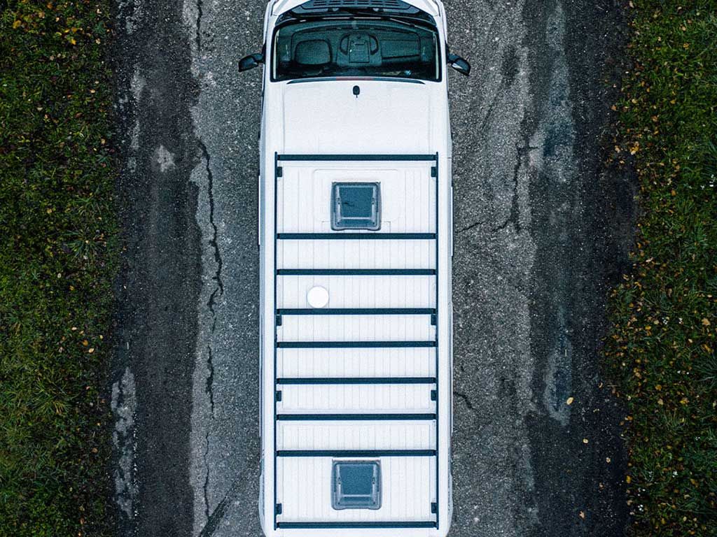 Top-down view of a white van with a cargo bed on a road.